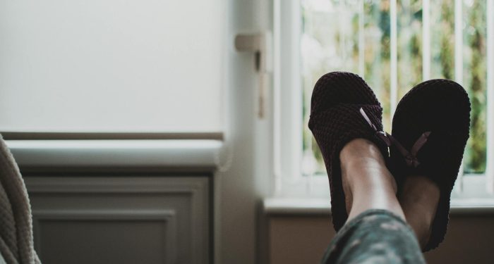 A cozy, relaxed atmosphere with feet in slippers up by a window, perfect for leisure and tranquility.