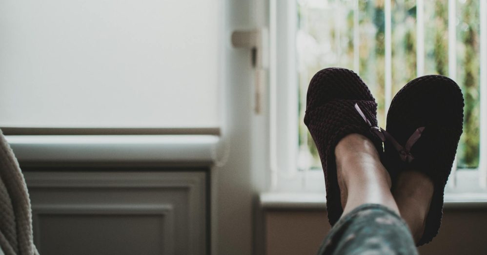 A cozy, relaxed atmosphere with feet in slippers up by a window, perfect for leisure and tranquility.