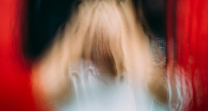 Through glass view of faceless person representing scary zombie near bright red blood fluids