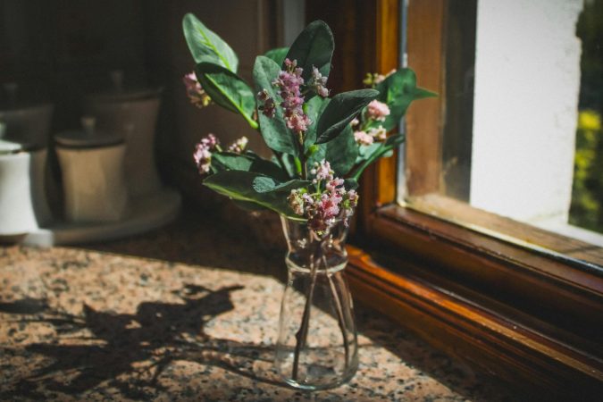 A vase of vibrant pink flowers on a sunlit window sill, creating a warm ambiance.