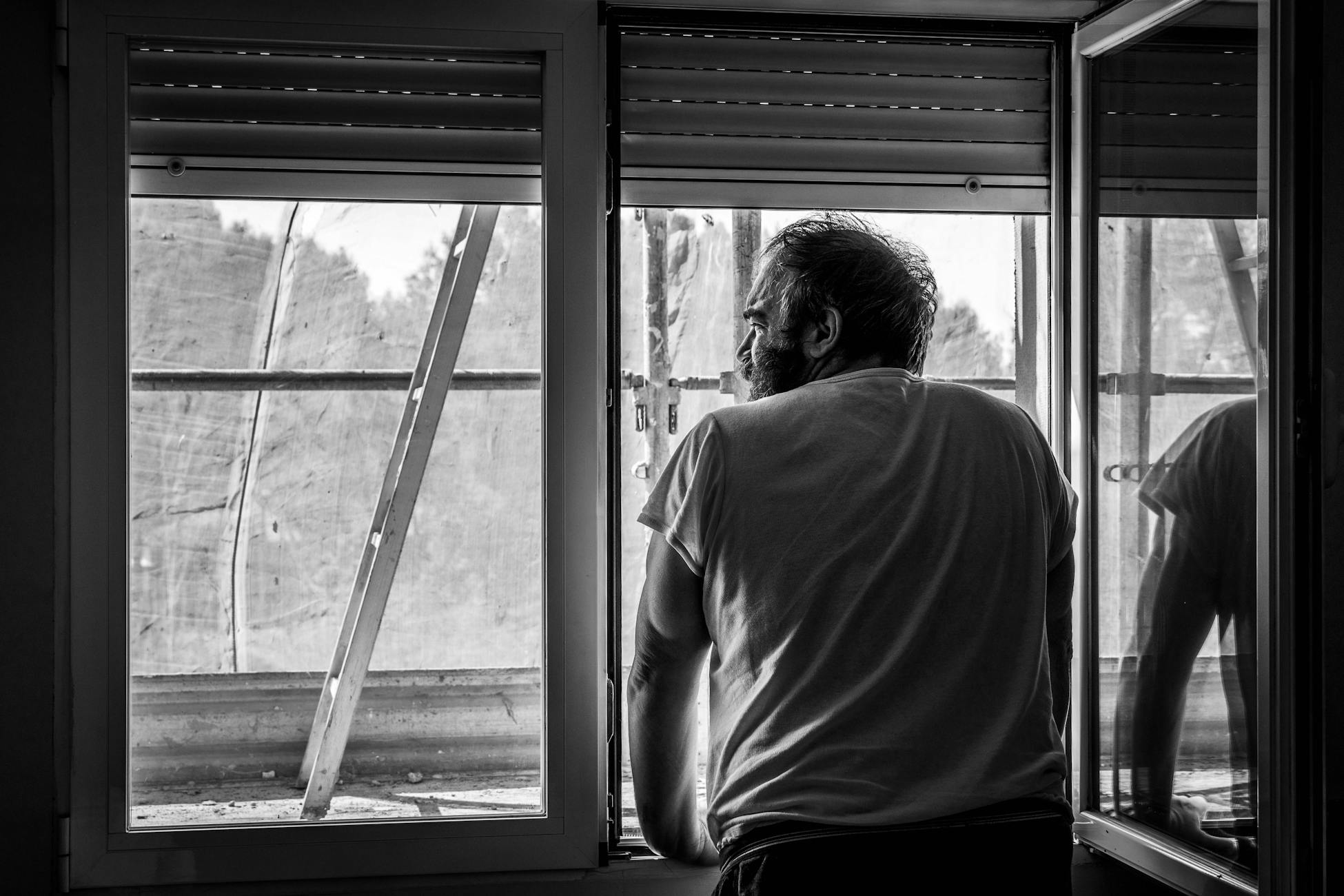 A man gazes outside, reflecting during quarantine indoors.