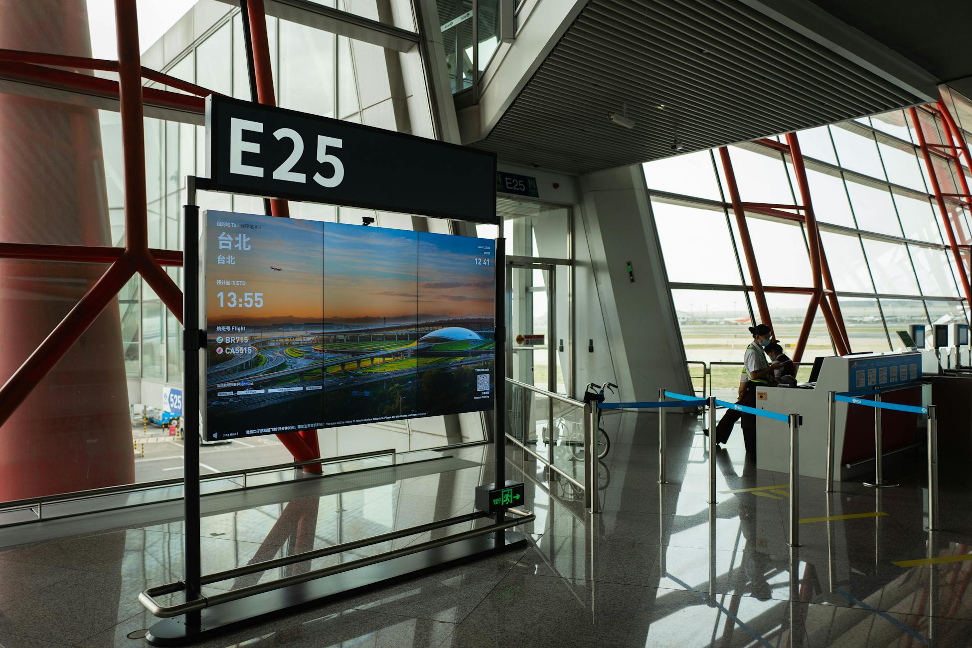 A view of a modern airport terminal showcasing Gate E25 with a flight display board.