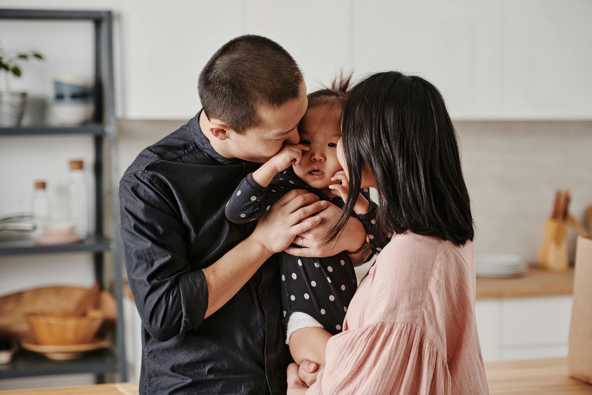 A loving Asian family shares a tender moment in their modern kitchen.