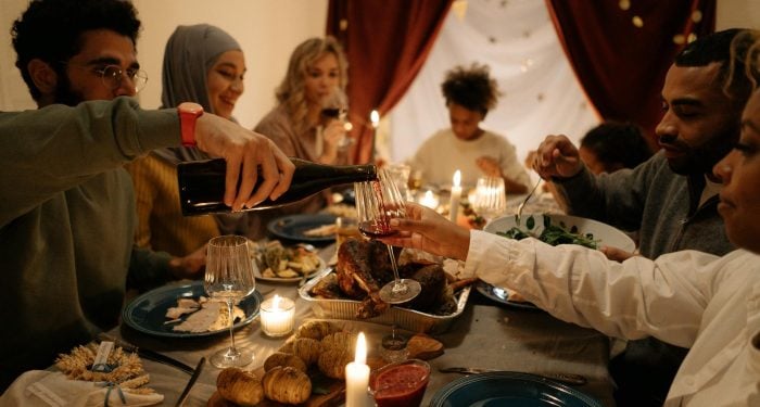 A family enjoying a festive dinner together, pouring wine with candles lit indoors.