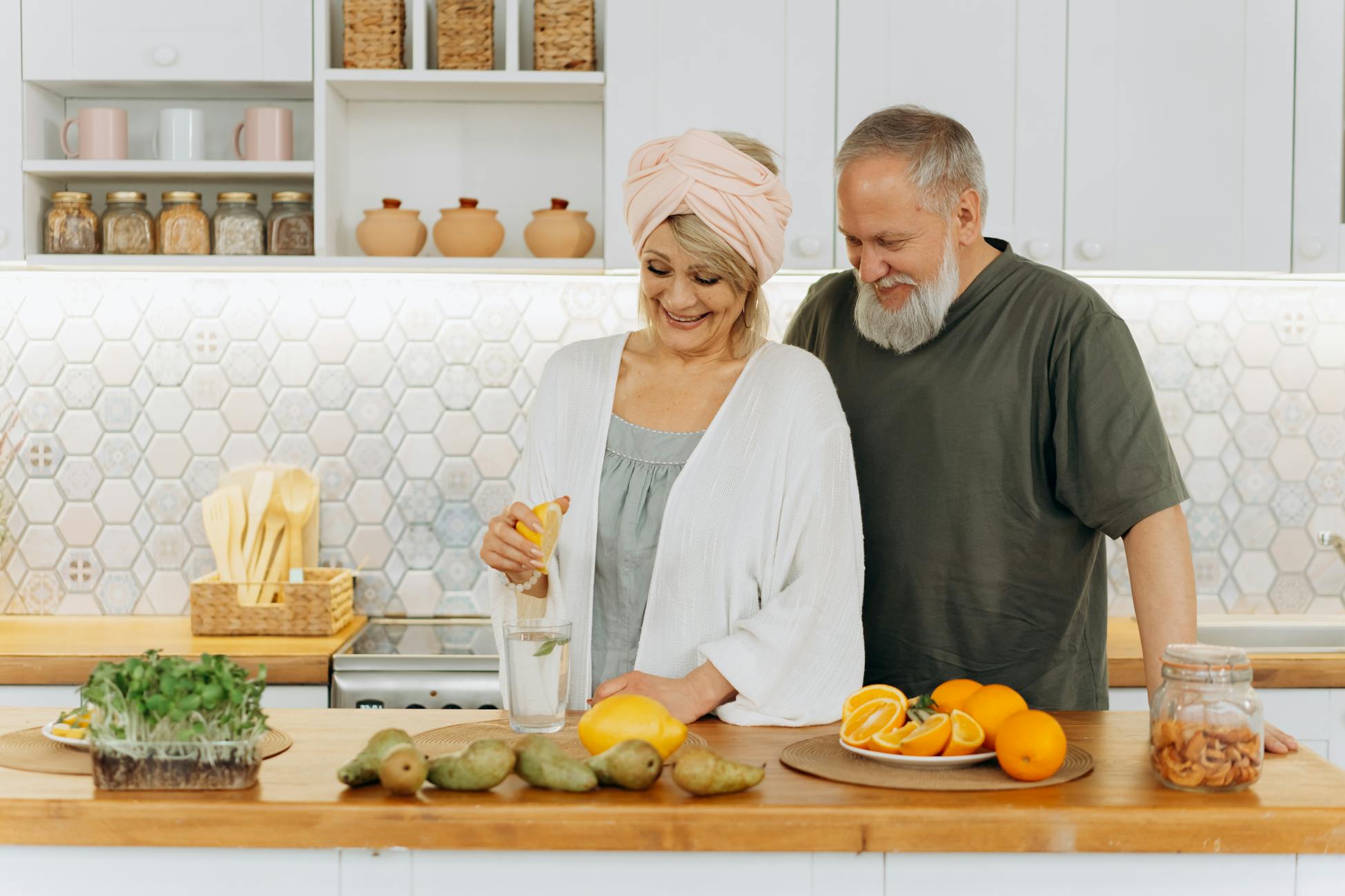 Senior couple squeezing citrus in a bright kitchen setting, promoting healthy living and joyful togetherness.