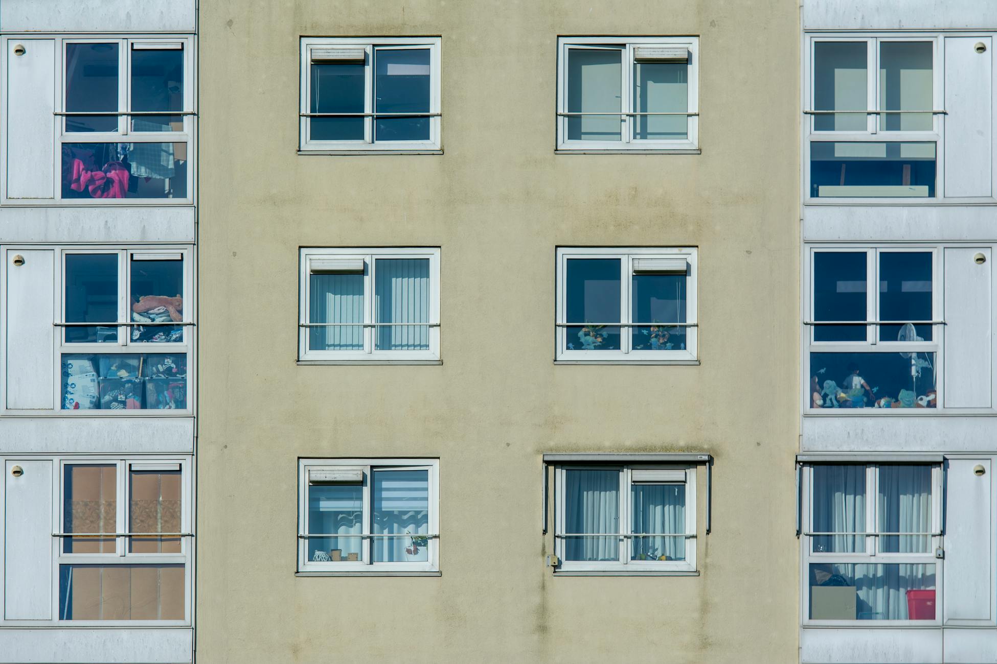 A detailed view of a modern apartment building's facade showcasing windows and balconies on a sunny day.