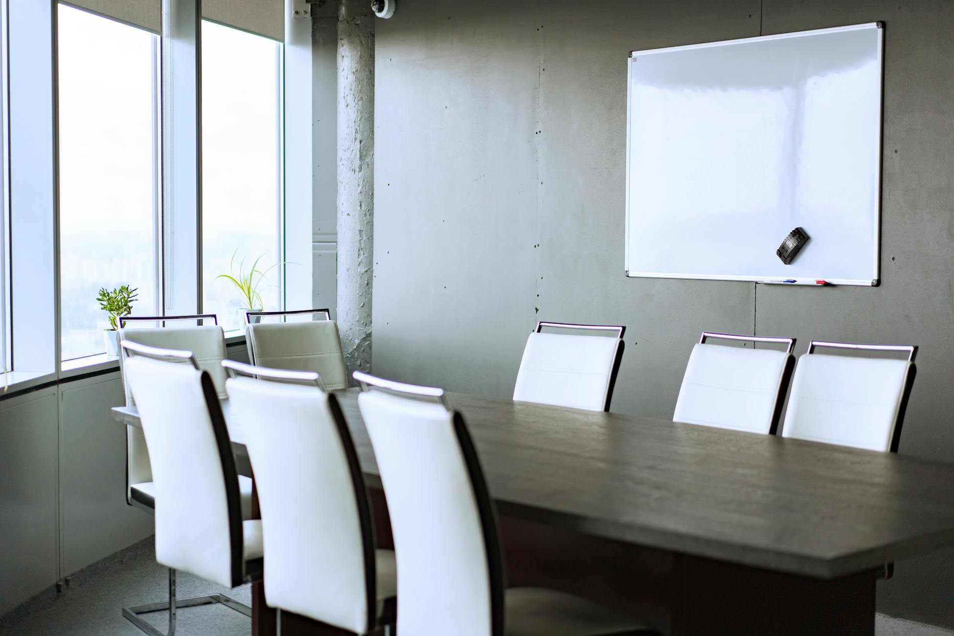 Spacious conference room featuring a modern whiteboard, sleek chairs, and large windows for natural light.