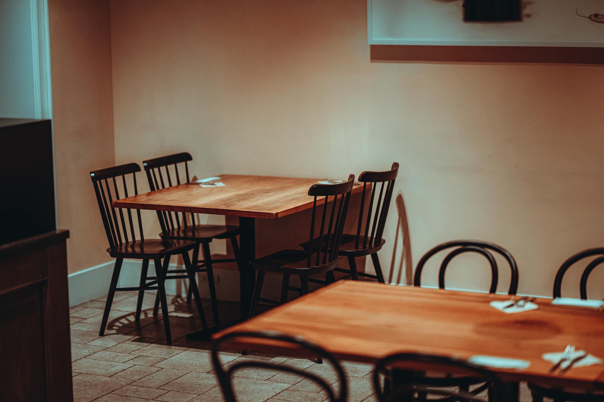A minimalist restaurant interior in Tokyo featuring wooden tables and classic chairs.