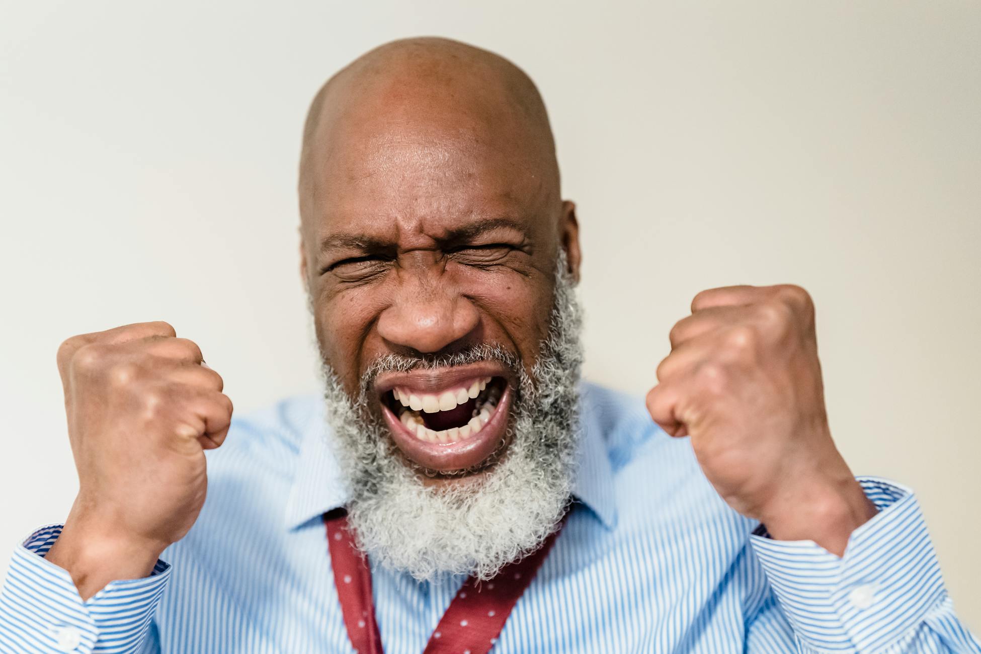 African American senior man showing excitement with clenched fists.