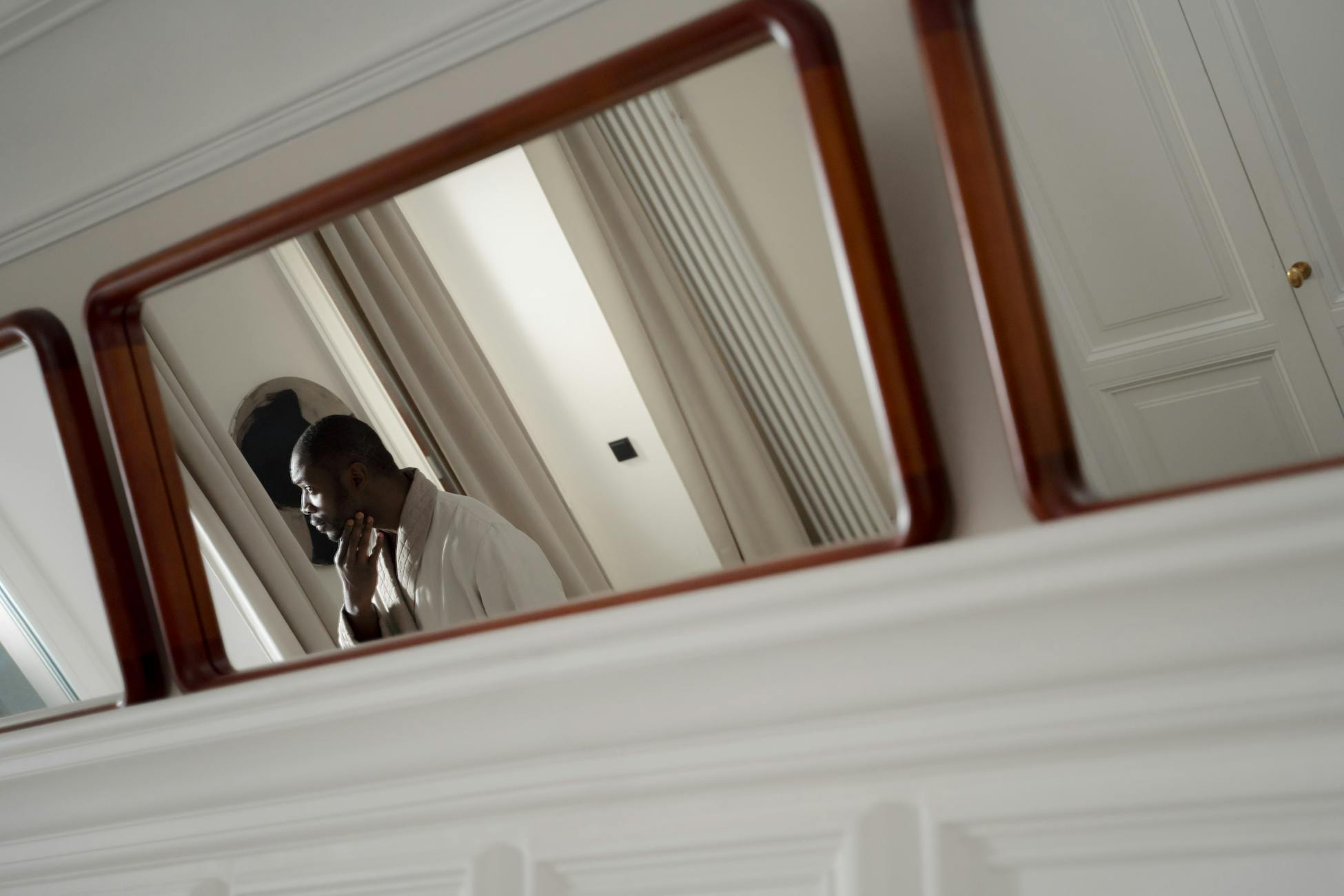 A man in deep thought, captured through his reflection in a home mirror, offering a moment of introspection.