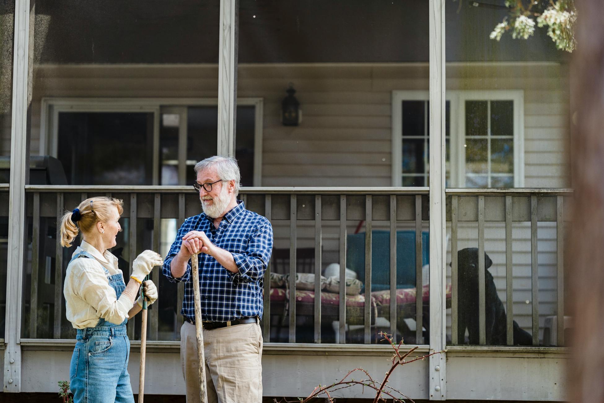 Senior couple gardening outside their home, enjoying a sunny day together.