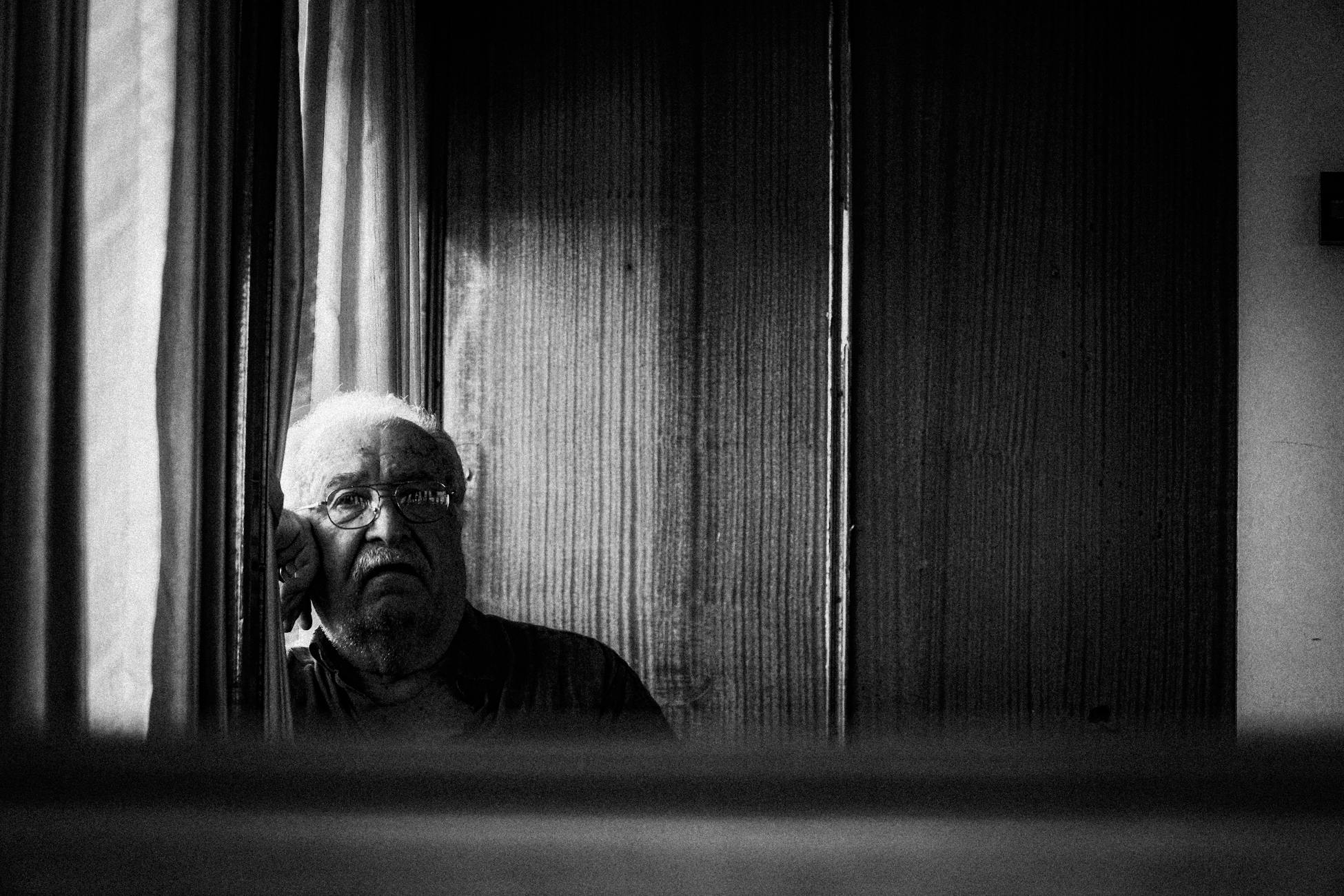 Moody black and white portrait of an elderly man gazing thoughtfully.