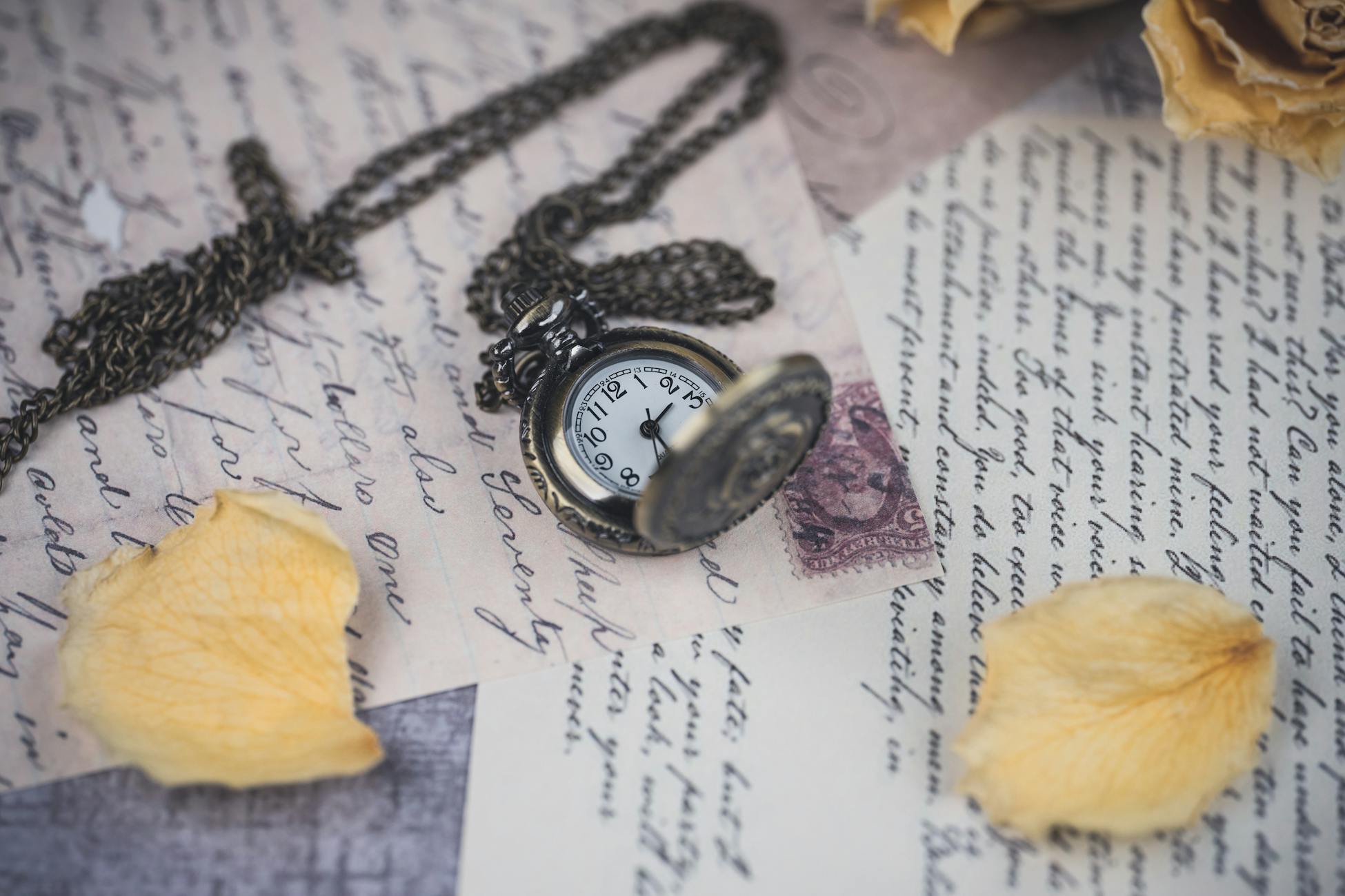 Antique pocket watch on old letters with dried rose petals, evoking nostalgia.