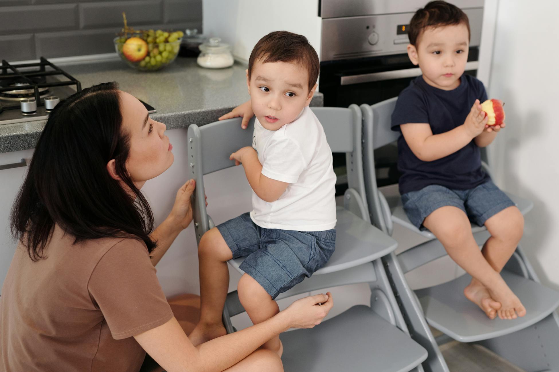 A mother and her children interacting in a modern kitchen, emphasizing family and quality time.