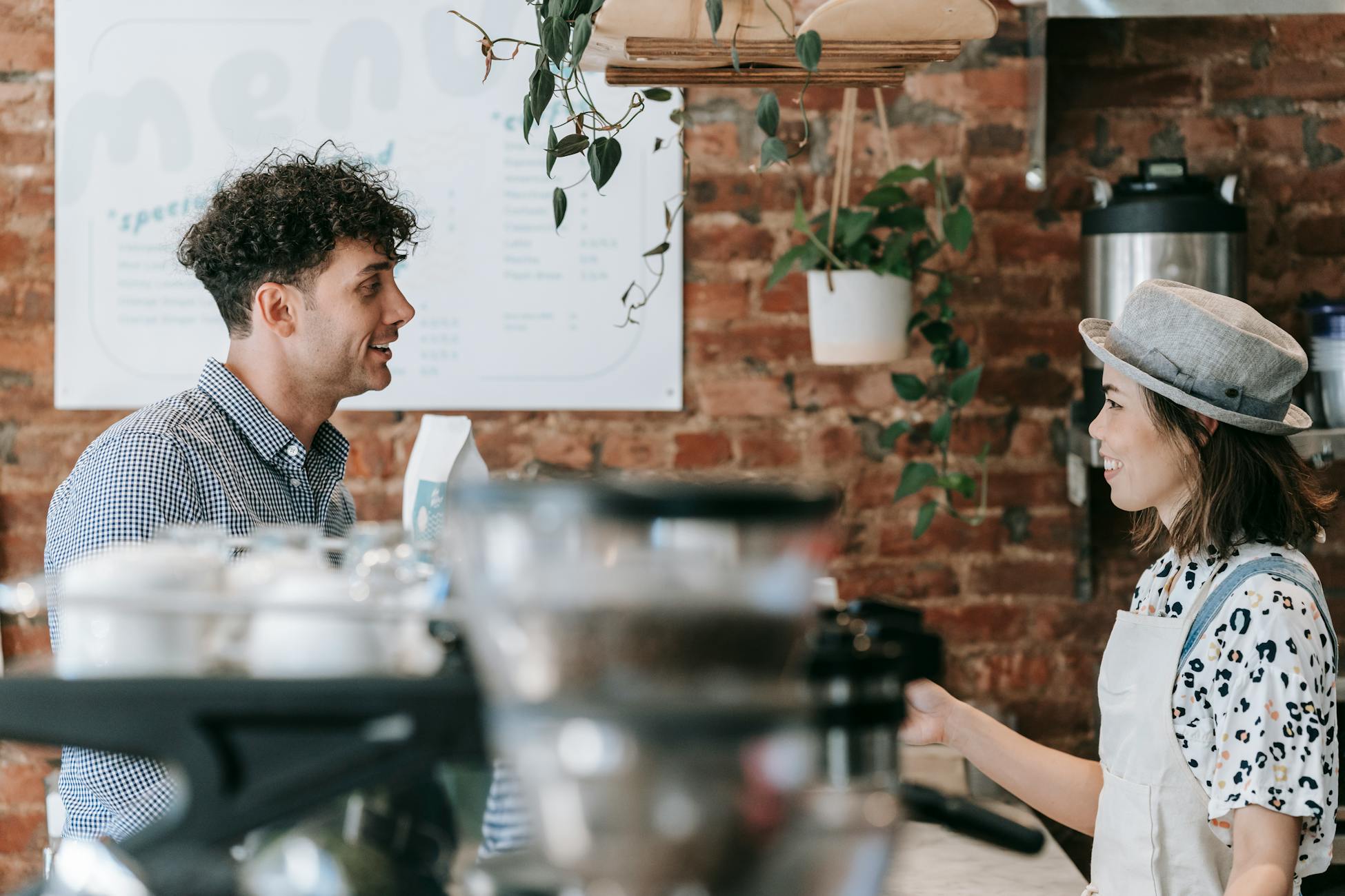 Smiling barista engaging in conversation with a customer in a cozy coffee shop.