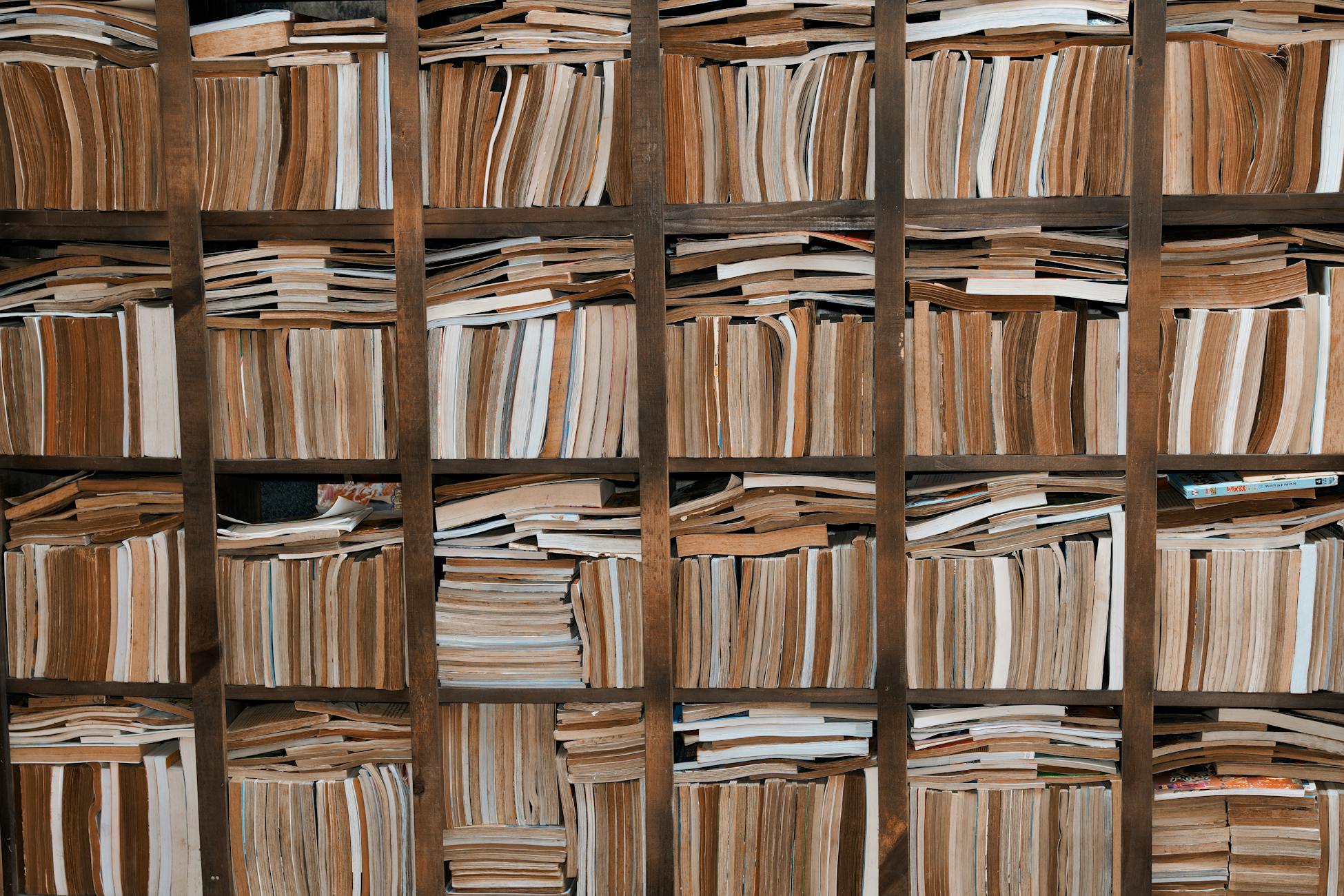 A large collection of books stacked horizontally on wooden shelves, perfect for educational themes.