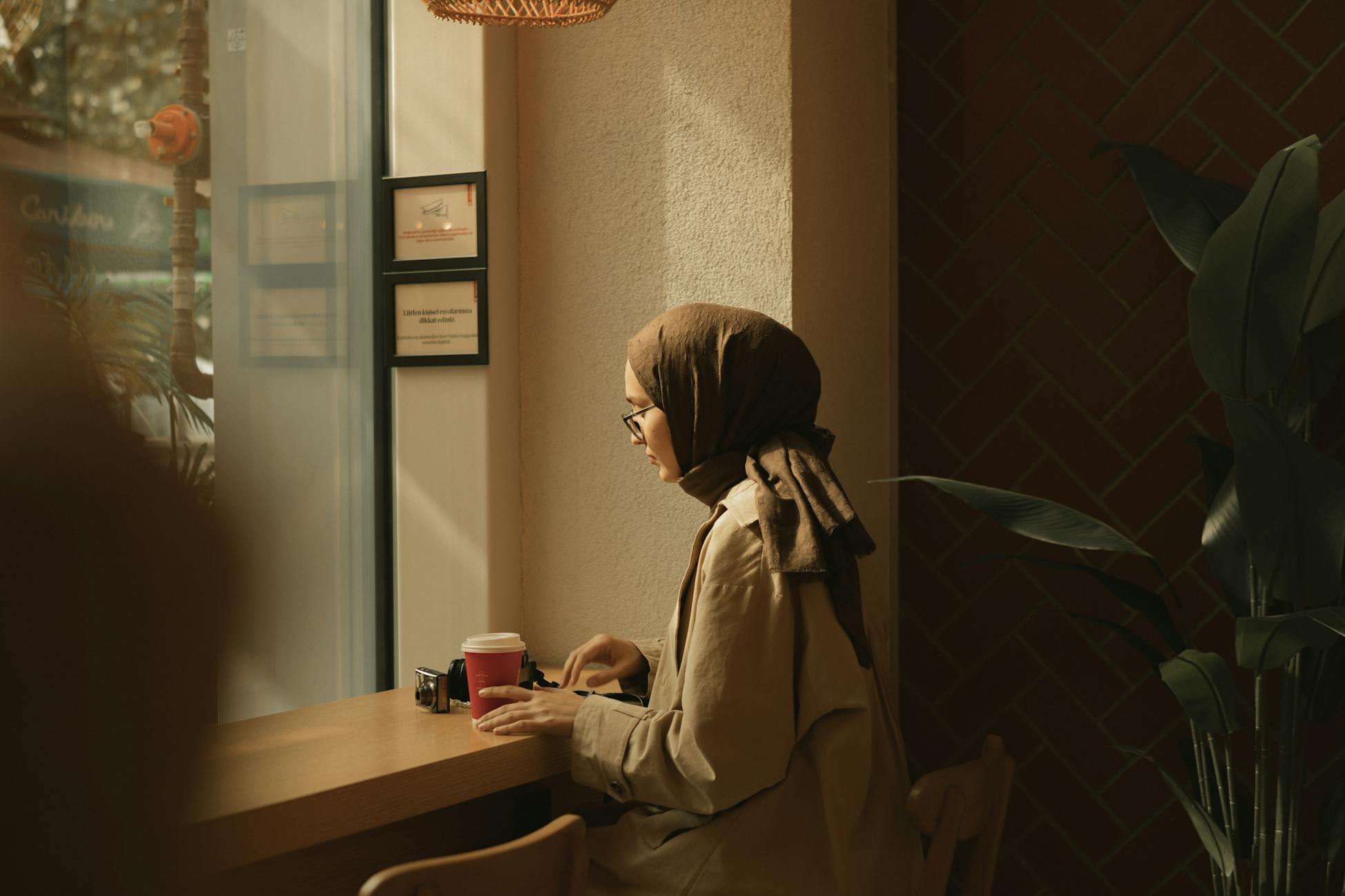 A young woman in a headscarf relaxes with a coffee in a cozy café.