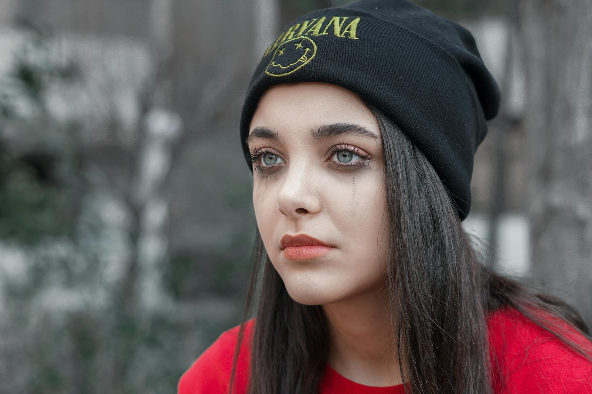 A contemplative young woman in a beanie, captured with a moody tone.