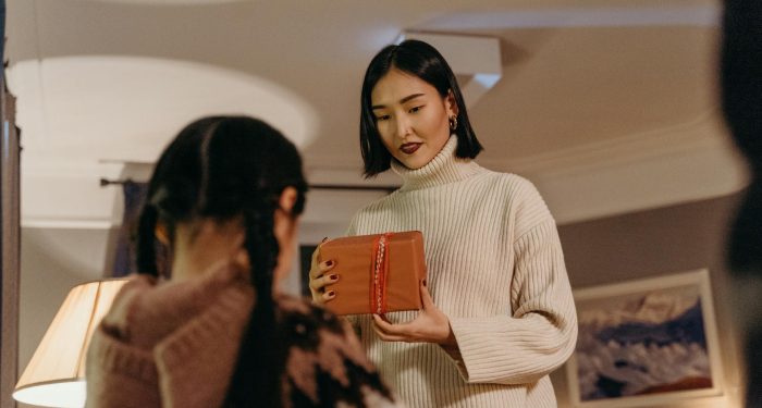 Mother and daughter share a special moment as they exchange a gift indoors.