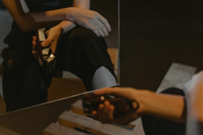 A person is reflected in the mirror holding an electric shaver indoors.