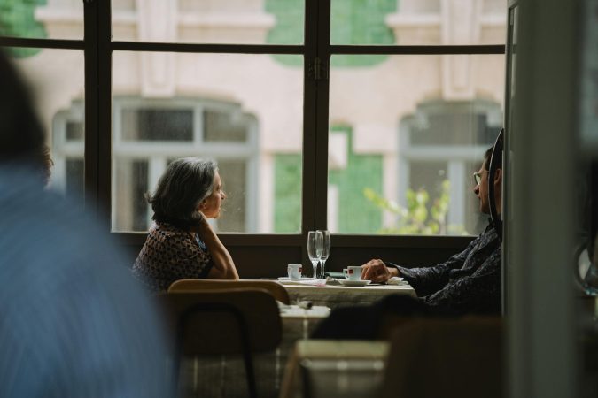 Elderly couple sitting by the window, enjoying coffee at a cozy café.
