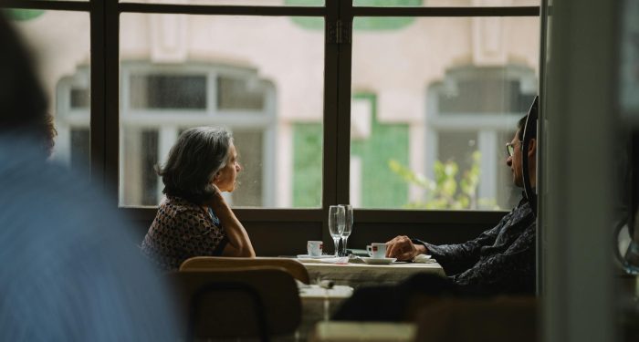 Elderly couple sitting by the window, enjoying coffee at a cozy café.