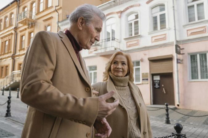 An elderly couple enjoys a stroll together on a charming European street.