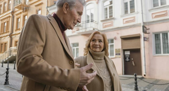 An elderly couple enjoys a stroll together on a charming European street.