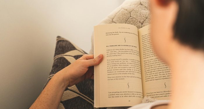 Woman enjoying relaxation by reading a book on a cozy couch indoors.