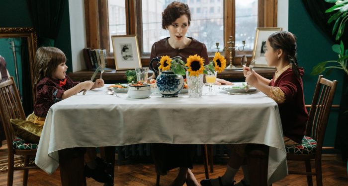 A family enjoys a meal together with sunflowers on the table, capturing a warm and inviting dining scene.