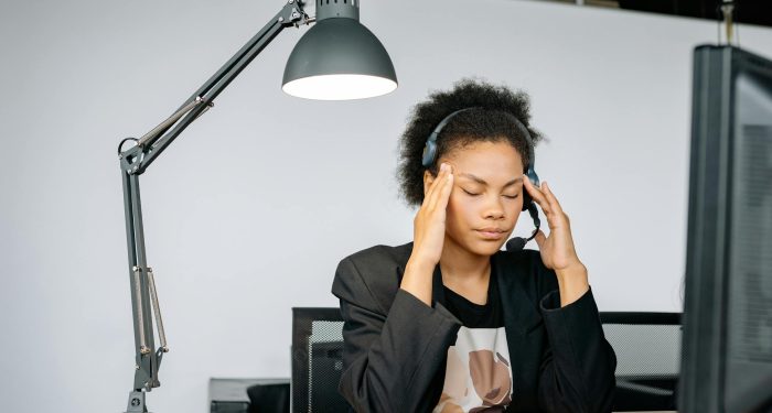 Exhausted call center agent with headset, tired from work, in an indoor office setting.