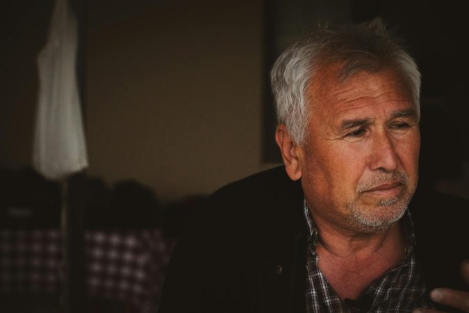 Portrait of an elderly man with white hair in a thoughtful pose, captured in Kızılkaş, Adana, Türkiye.