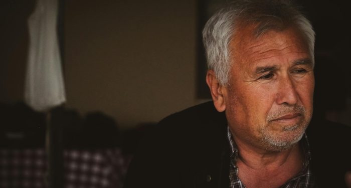 Portrait of an elderly man with white hair in a thoughtful pose, captured in Kızılkaş, Adana, Türkiye.