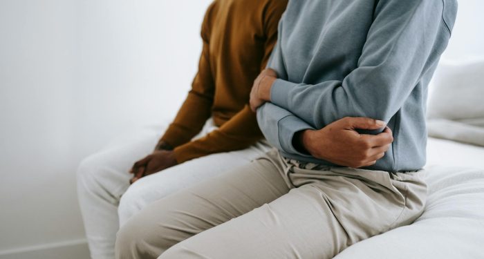 Crop faceless young black couple in casual outfit resting together in bedroom in daytime