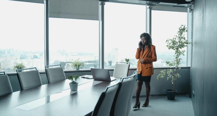 Elegant woman in office attire talks on phone in a stylish conference room.