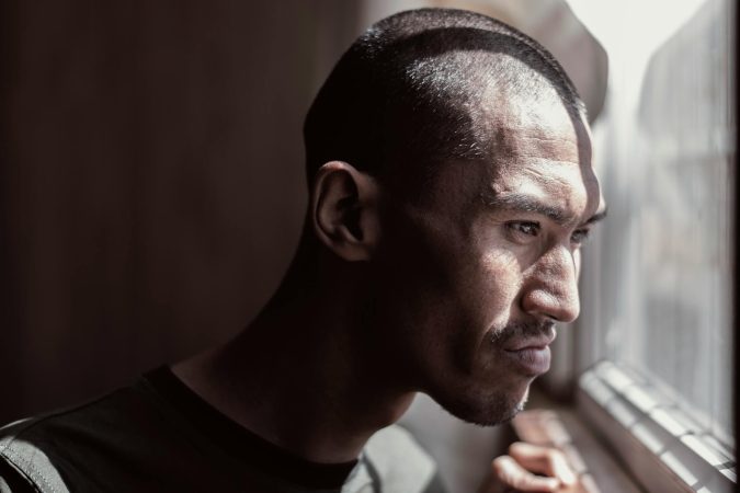 Portrait of a contemplative man looking out the window, bathed in natural light.