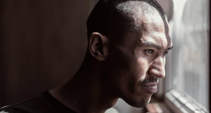 Portrait of a contemplative man looking out the window, bathed in natural light.