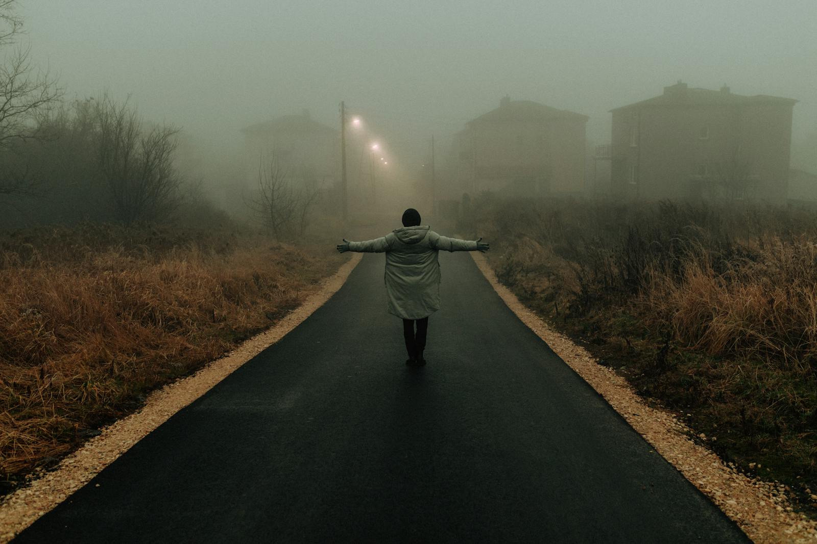 person standing crossroads foggy