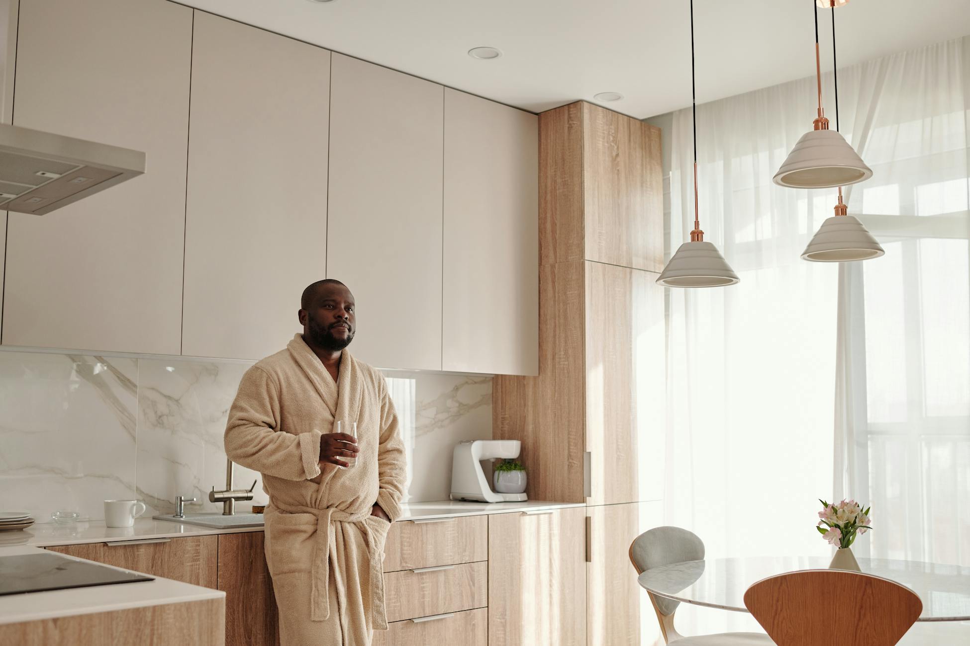 Man in bathrobe enjoys morning coffee in stylish kitchen. Bright and serene atmosphere.